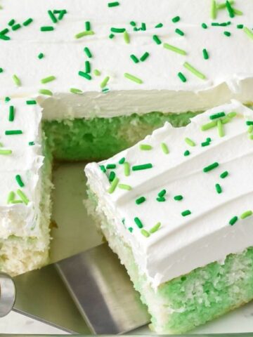 a slice of white cake on a plate with ribbons of lime jello with cool whip topping.