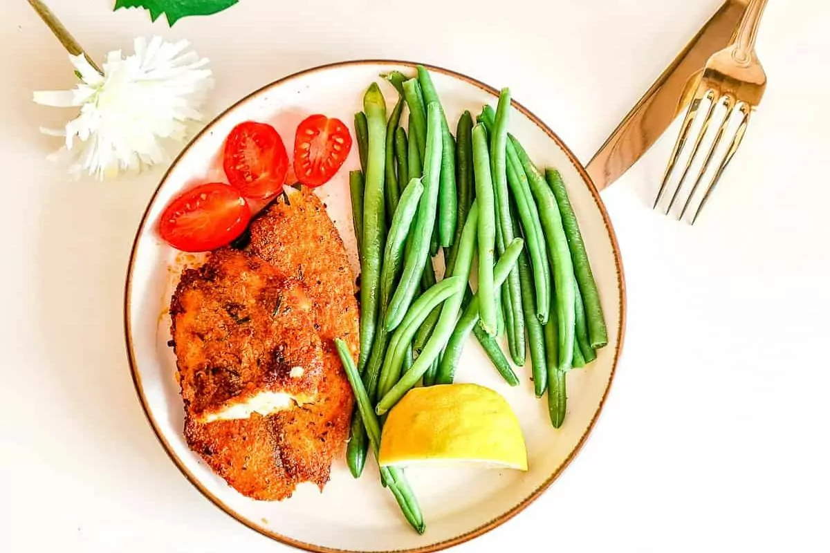 a plate of green beans, tomatoes and air fryer fish filets.