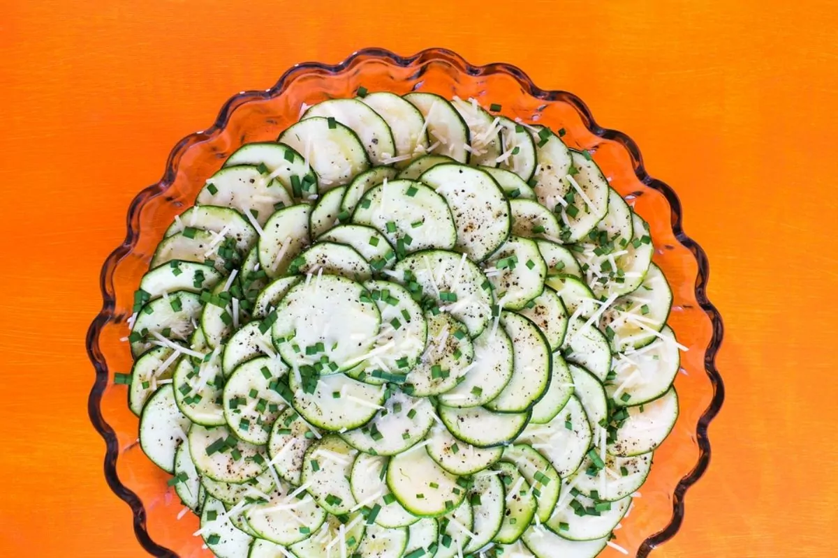 sliced zucchini in a circle pattern in a round dish with chopped chives.