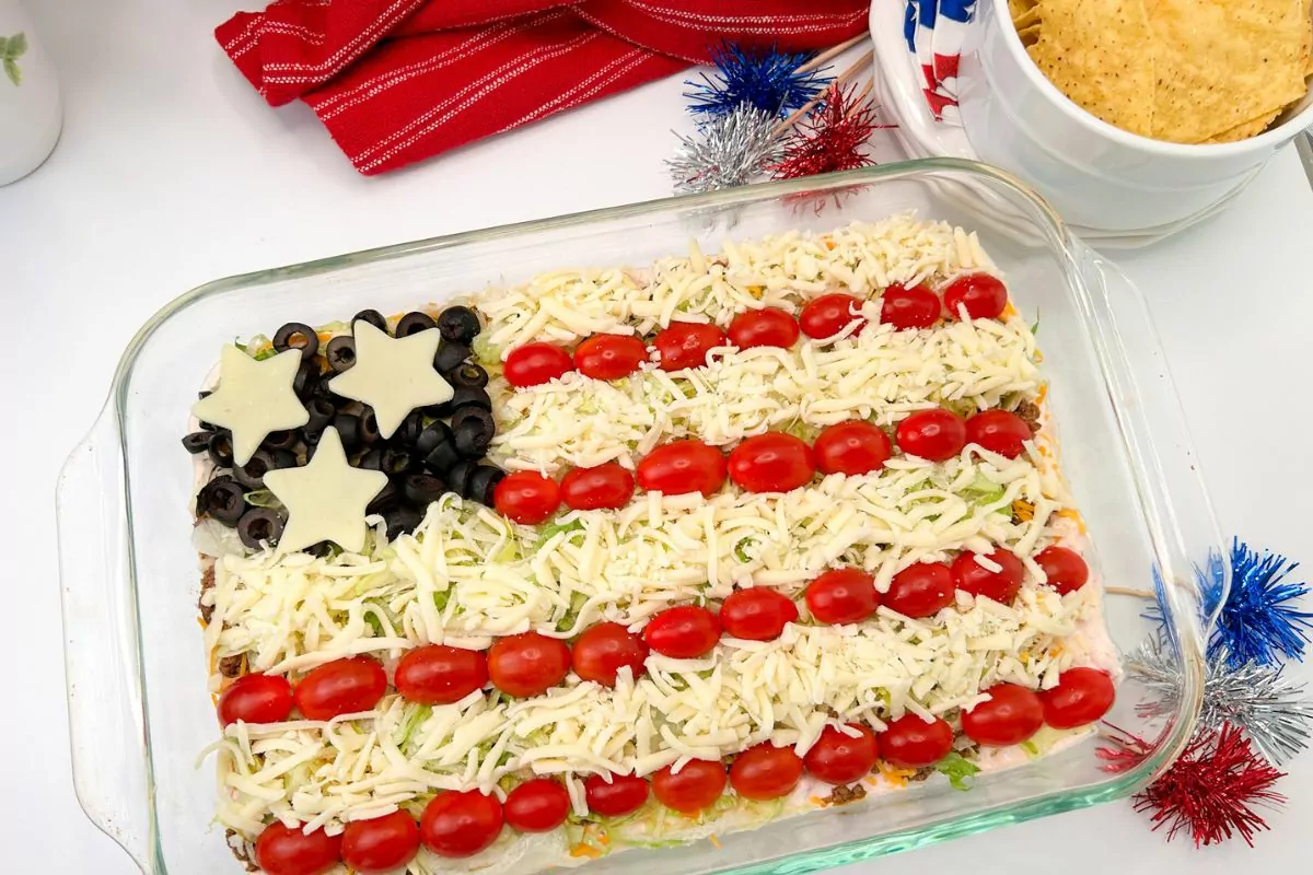 Close-up of a festive Patriotic Taco Salad, layered with ground beef, cheese, lettuce, and tomatoes arranged to resemble the American flag.