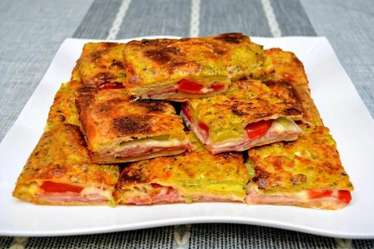 a plate of pastry squares with peppers, meat and cheese.