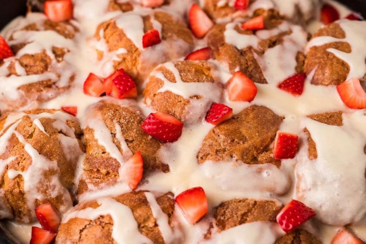 A skillet of baked french toast casserole with diced strawberries over the top.