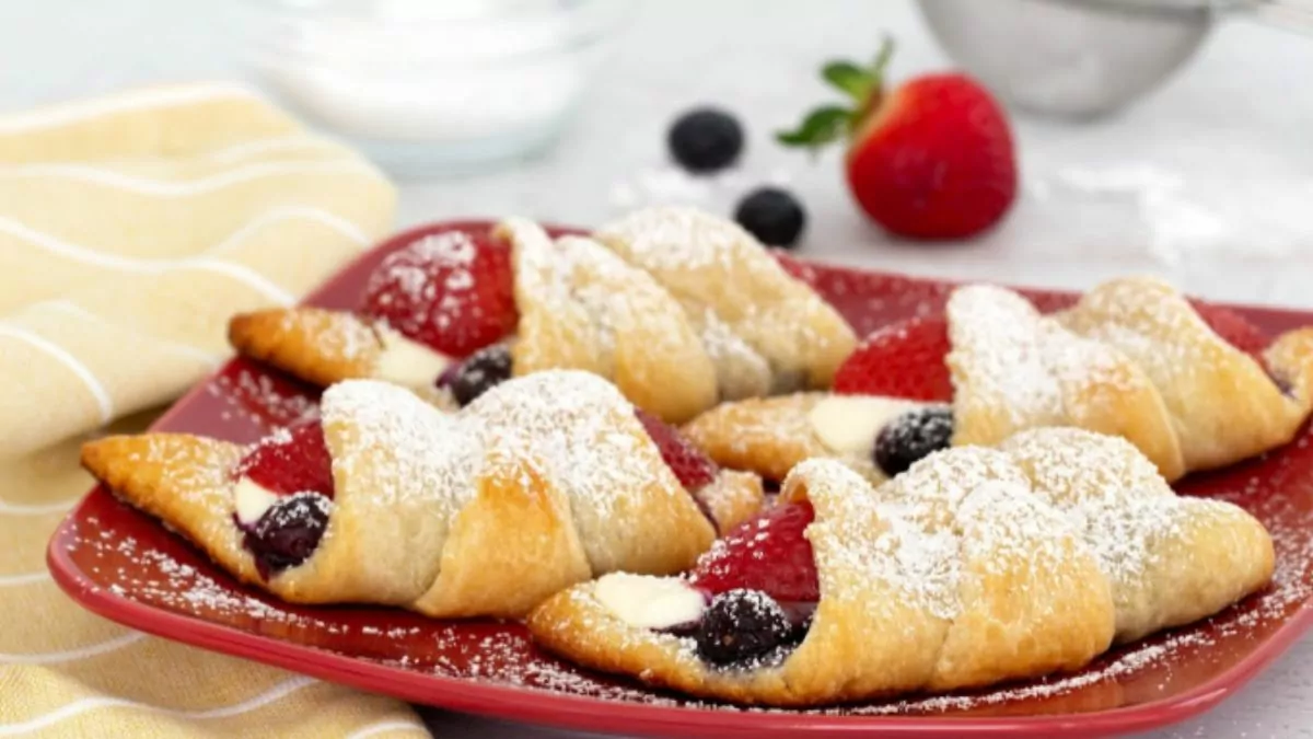 a plate of crescent rolls filled with cheese and fresh berries.