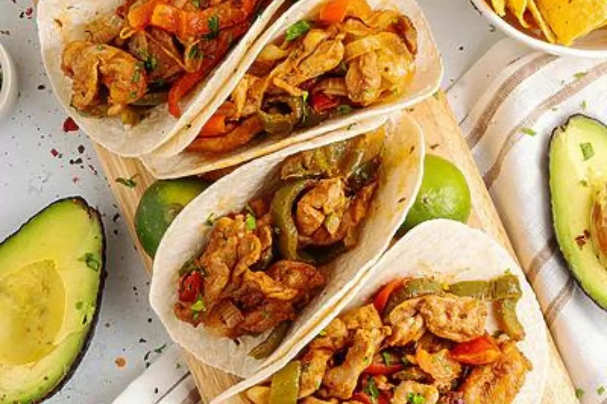 Fajitas made with chicken chunks, peppers and onions, on a plate.