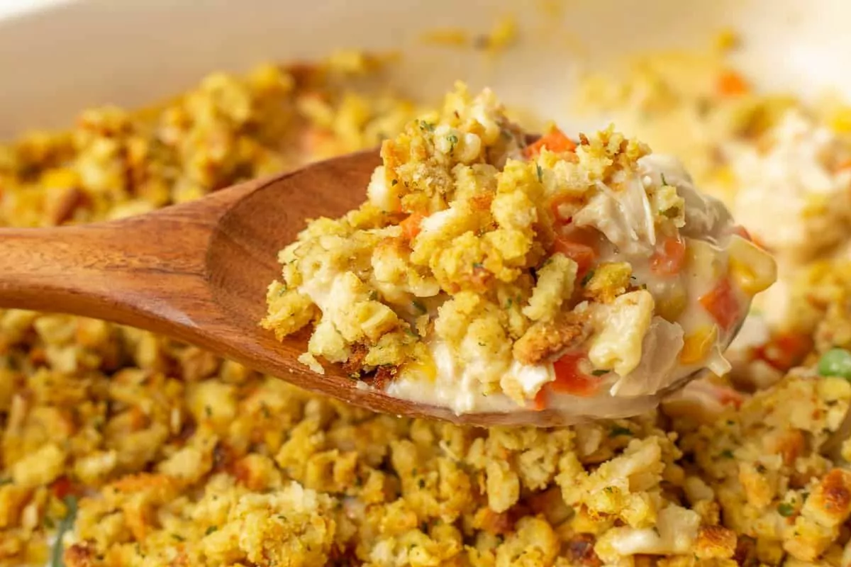 a serving spoon scooping chicken and stuffing casserole from a serving dish.