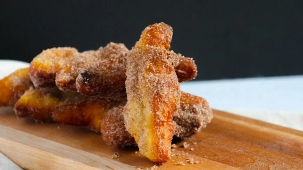 a wooden board with cheater churros covered in cinnamon and sugar.