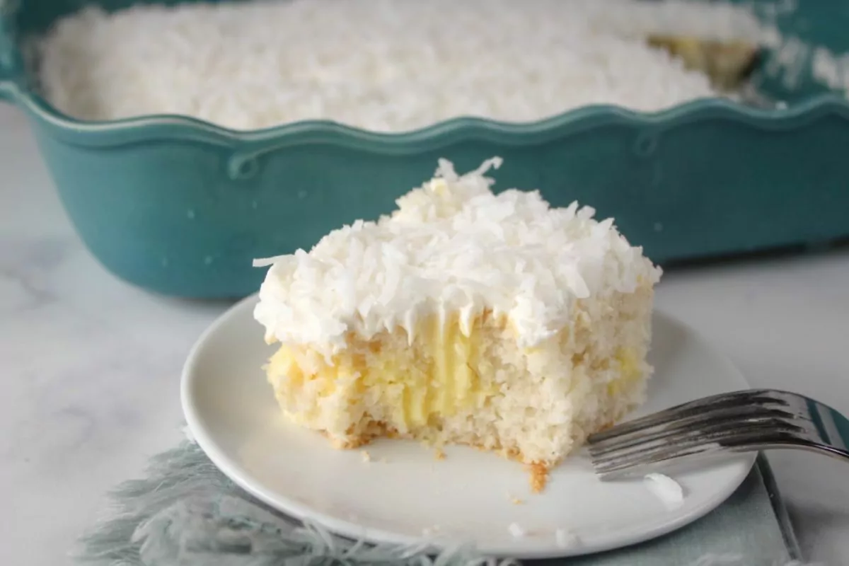 a slice of white cake with pudding in the center and shredded coconut over the top.