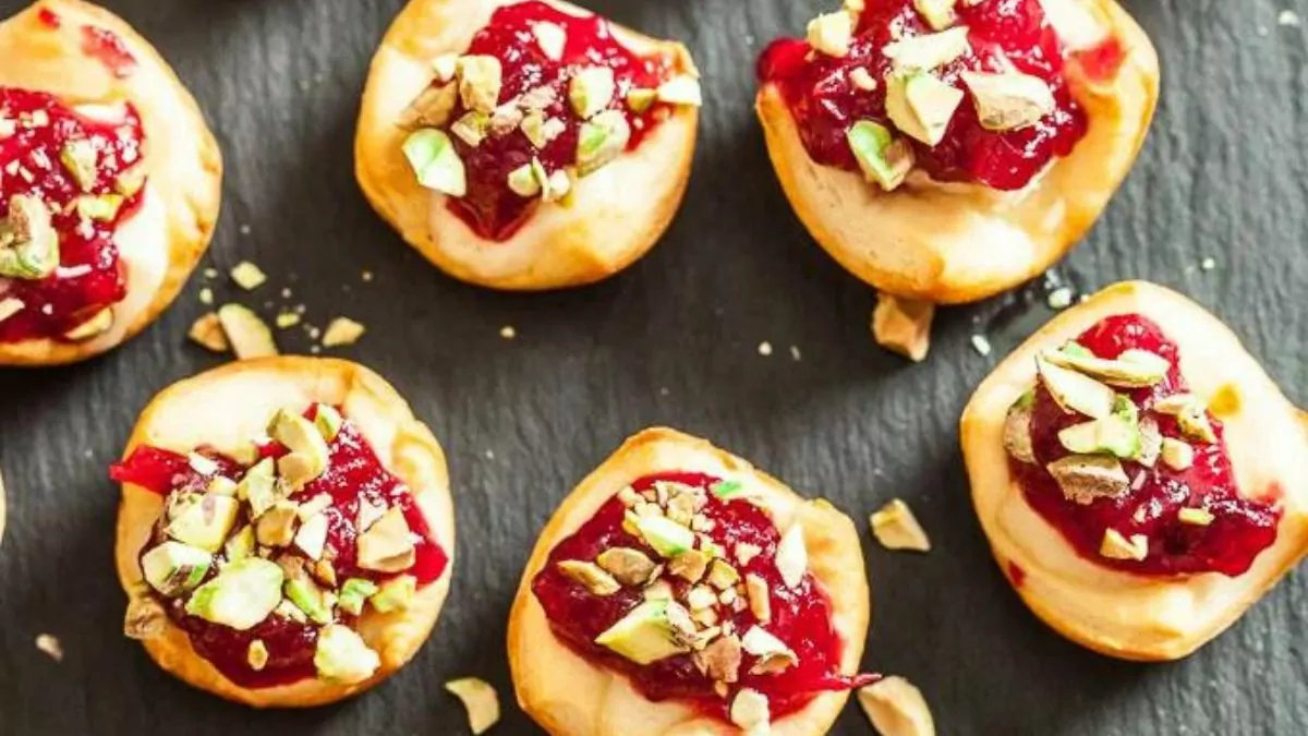 a serving of cranberry pineapple brie ring being dipped into cranberry sauce.