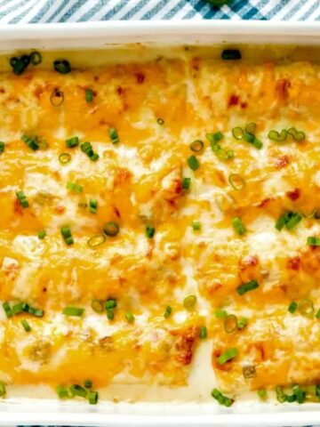 chicken enchiladas with white cream sauce in casserole dish.