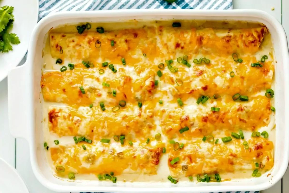 chicken enchiladas with white cream sauce in casserole dish.