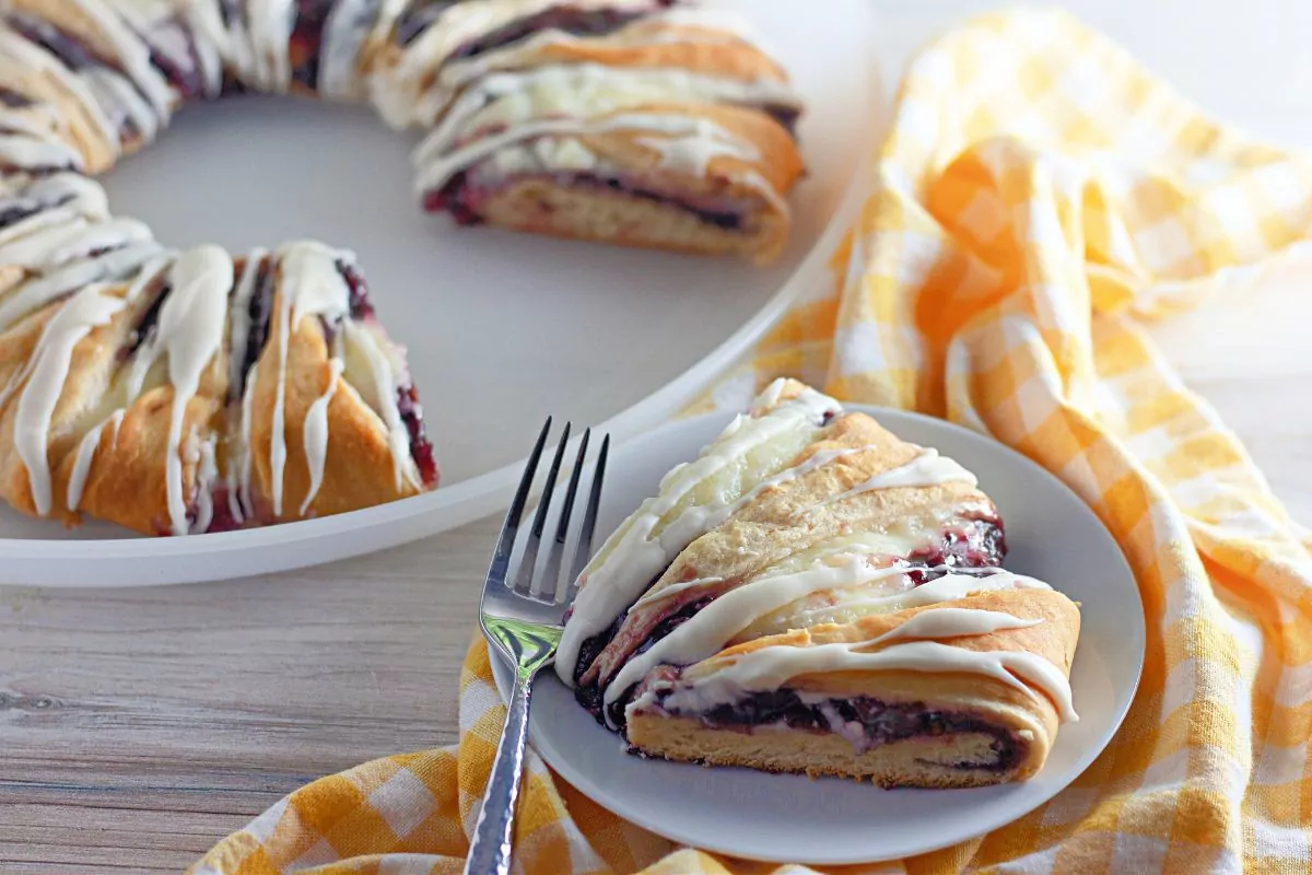 sliced danish with raspberry pie filling on plate with fork.