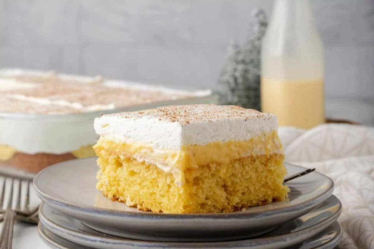 a slice of yellow cake with eggnog pudding and whipped cream layers.