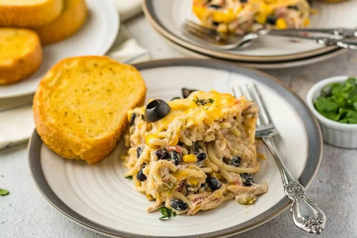 a plate of chicken pasta bake with black olives over the top.