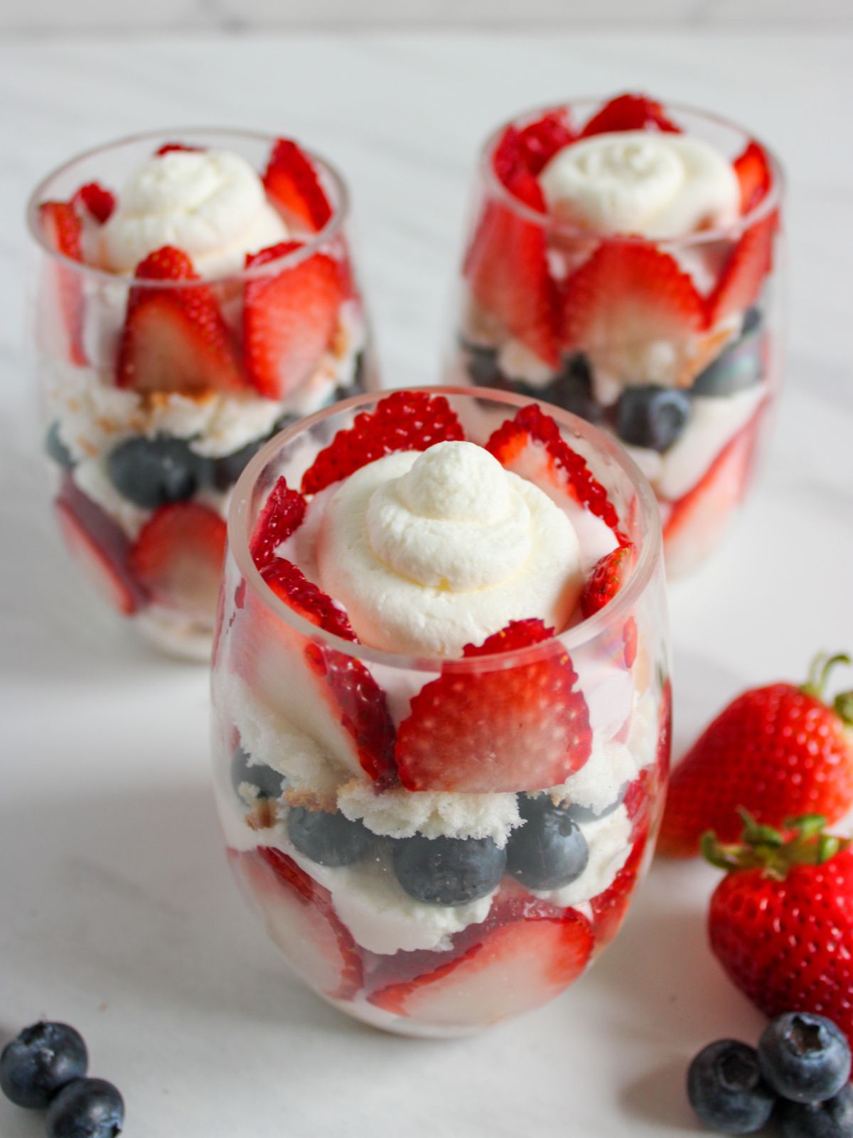 3 glasses of berries and whipped cream parfaits.