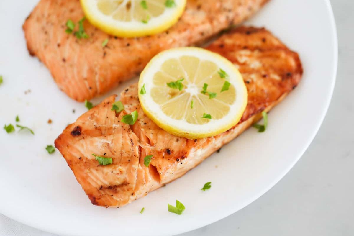 a plate with salmon filets, grilled with lemon on top