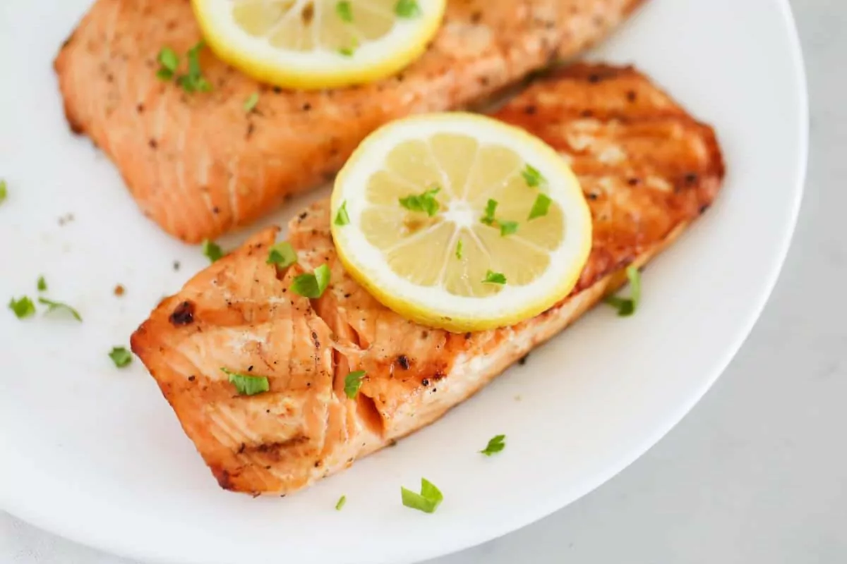 a plate with salmon filets, grilled with lemon on top