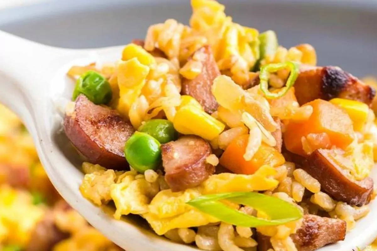 a spoon of fried rice with veggies and hot dog slices.