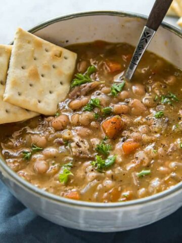 a bowl of bean soup with a spoon and crackers.