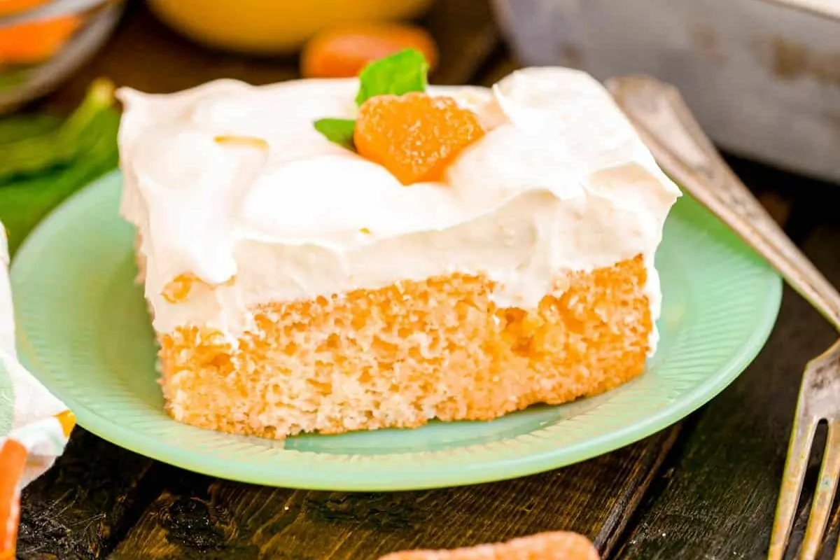 a slice of orange cream poke cake on a plate.