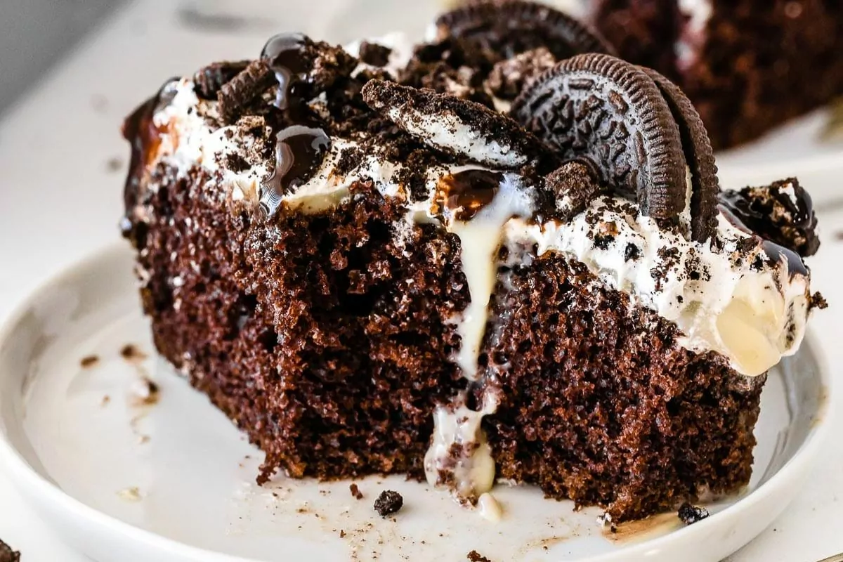 a slice of chocolate cake with cool whip frosting and oreo cookie crumbs.