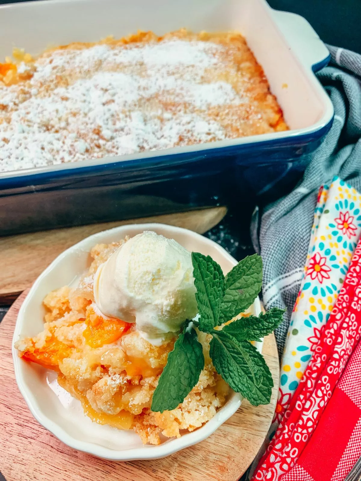 peach cobbler in white bowl with sprig of fresh mint.