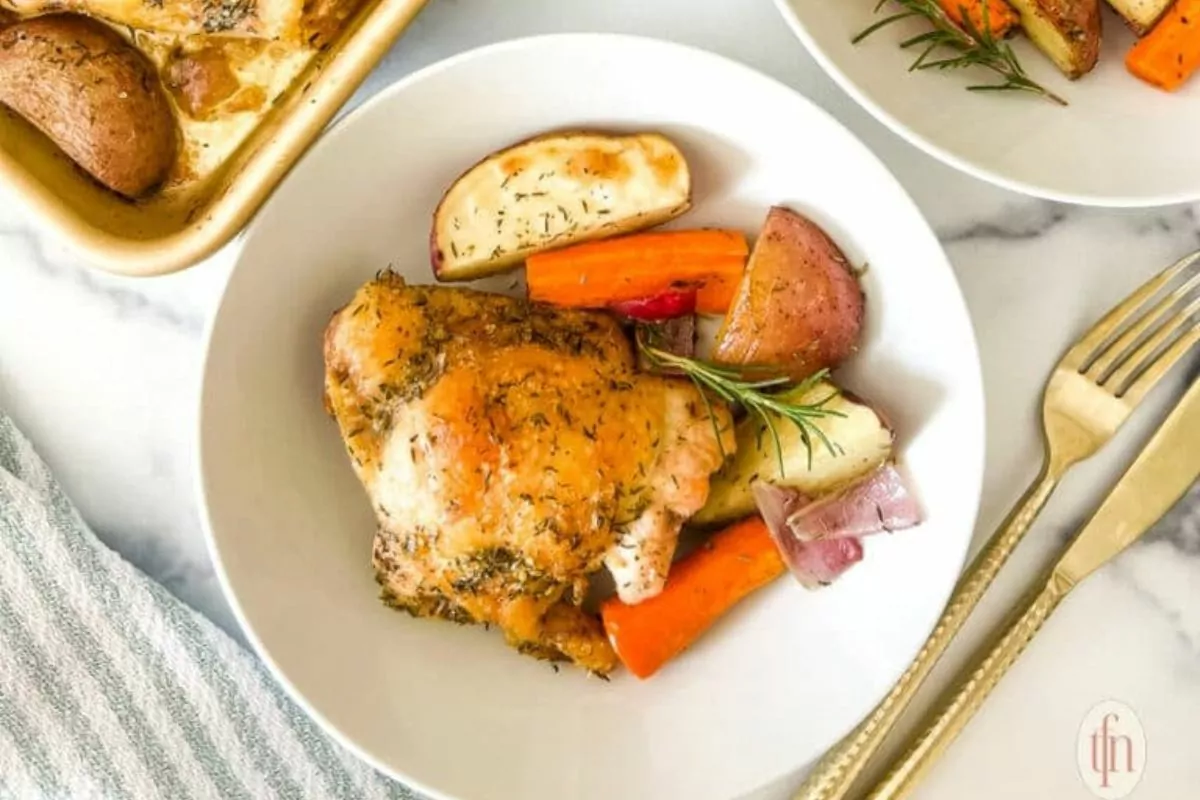 a sheet pan chicken dinner with carrots, potatoes and onions on a plate.