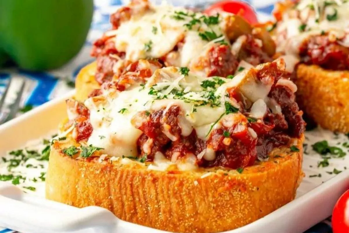 a sloppy joe piled onto a slice of thick garlic bread with cheese over top.