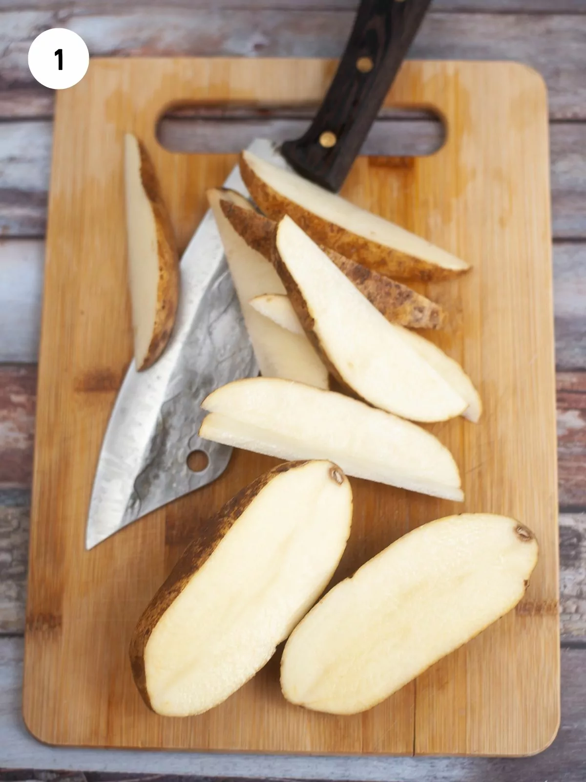 potatoes being cut into wedges on a wooden cutting board