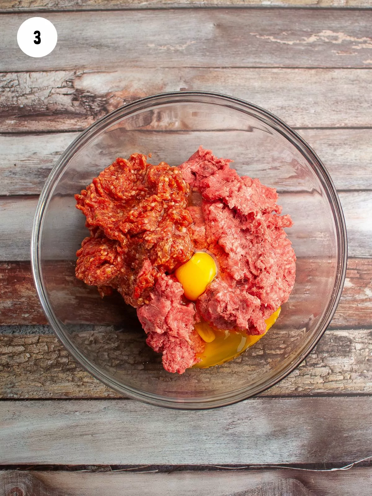 eggs added to the meats in a mixing bowl