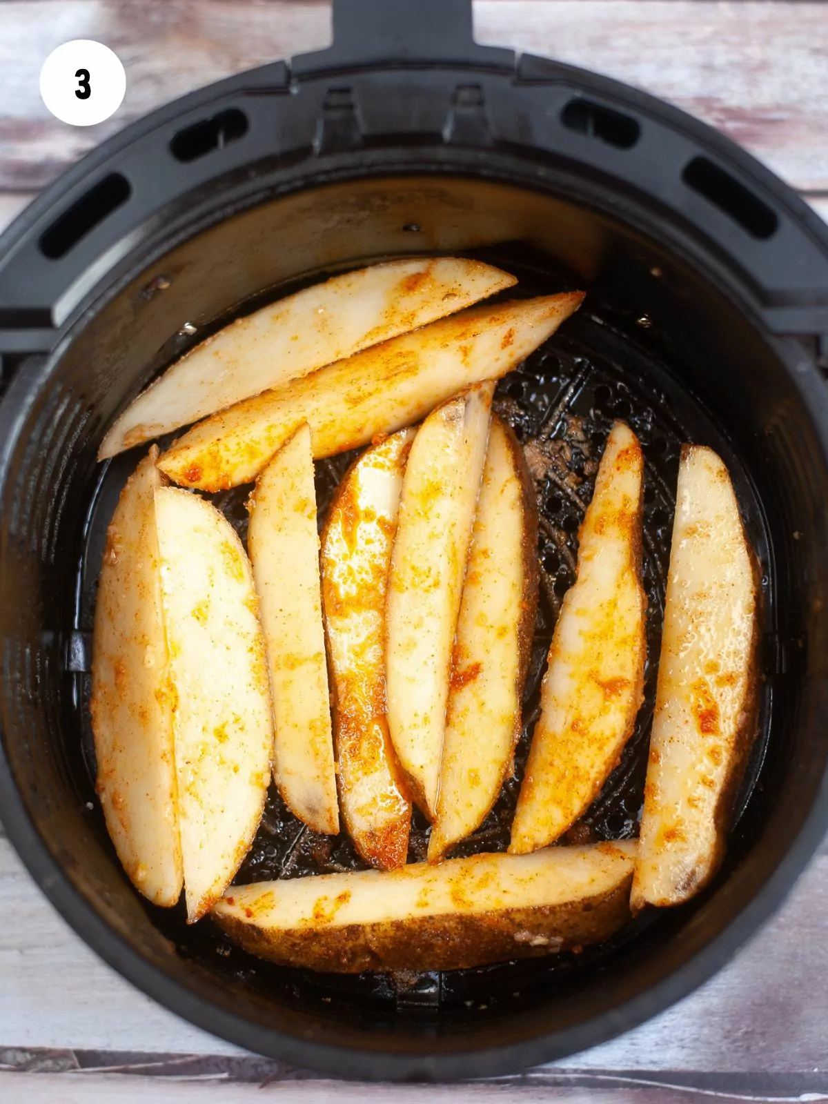 raw potato wedges in the basket of an air fryer