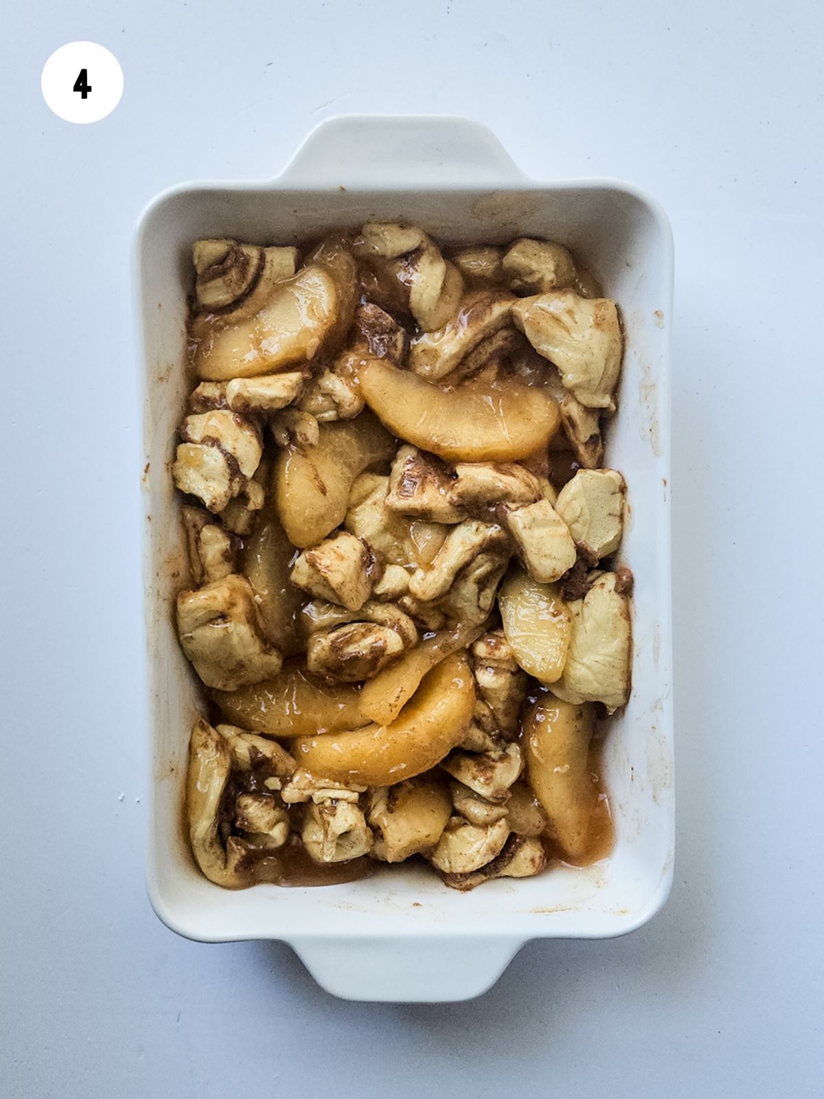 cut up cinnamon rolls and apple pie filling mixed in a casserole dish