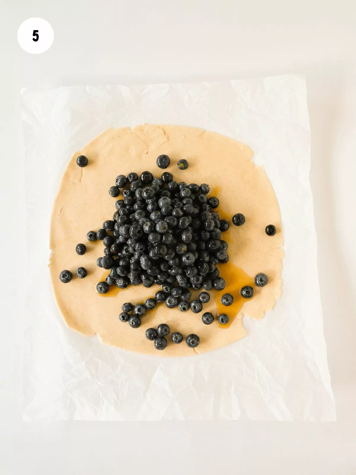 dough rolled out in a disc with blueberry filling placed in the middle