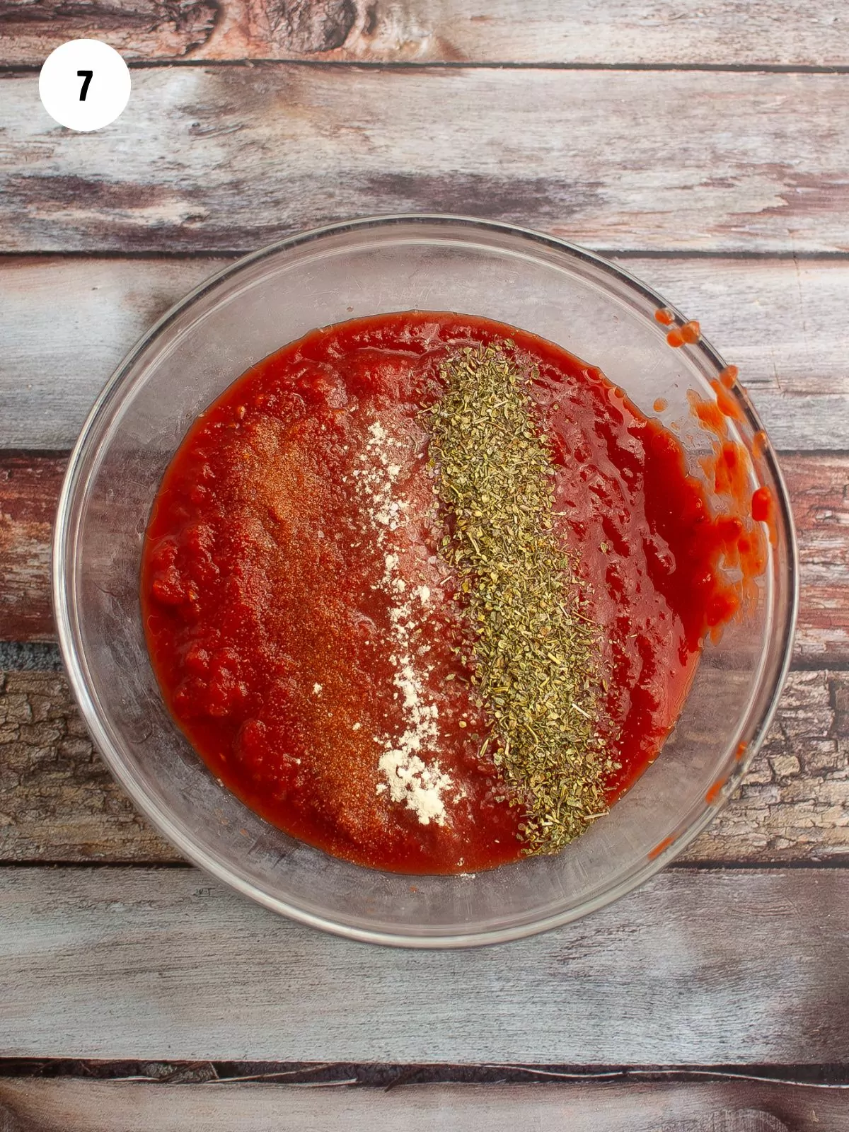 mixing bowl of crushed tomatoes with spices added on top