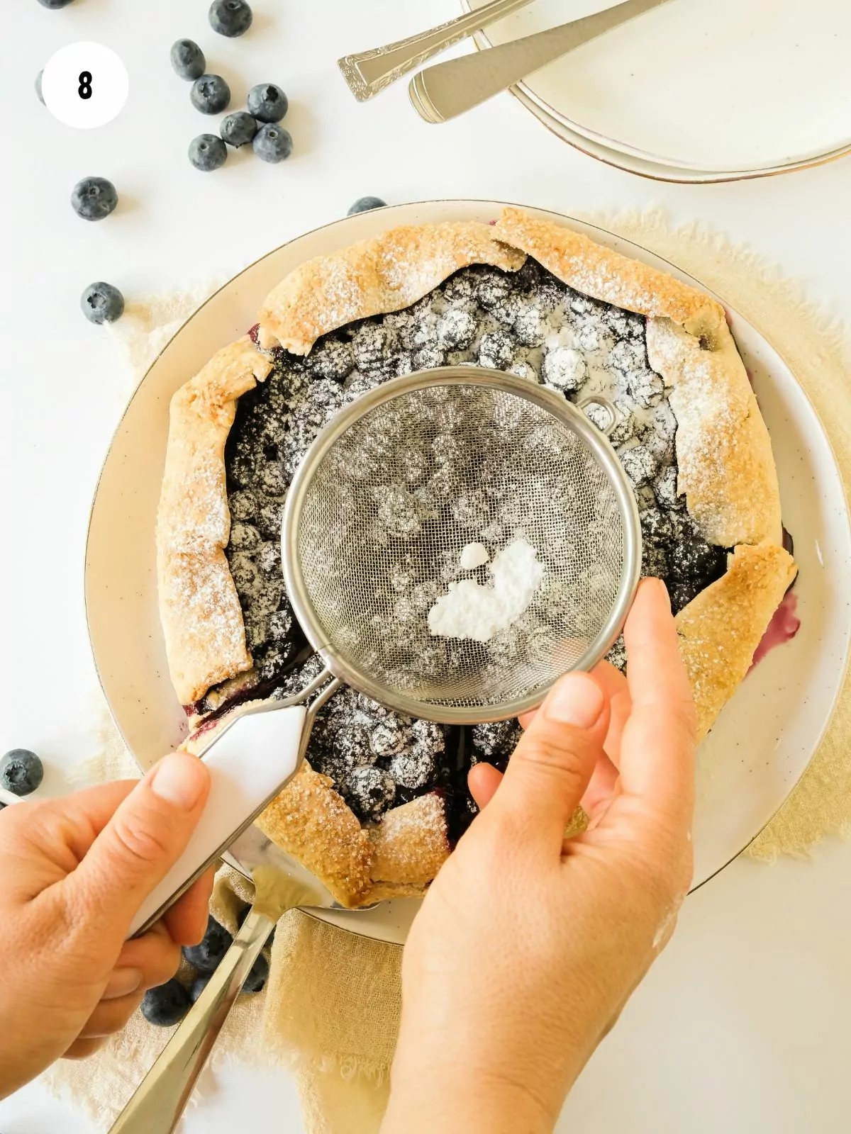 powder sugar being dusted with a sieve onto the galette