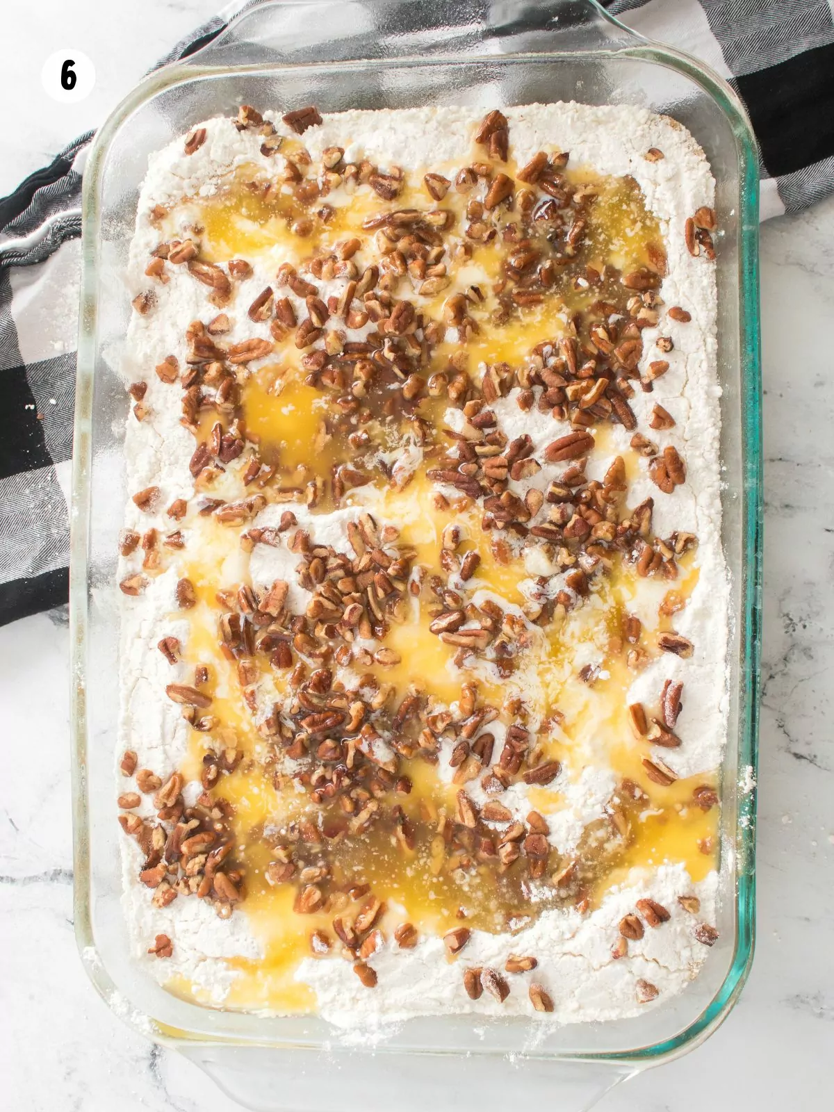 cake mix, melted butter, chopped pecans on top of cake batter in glass baking dish.