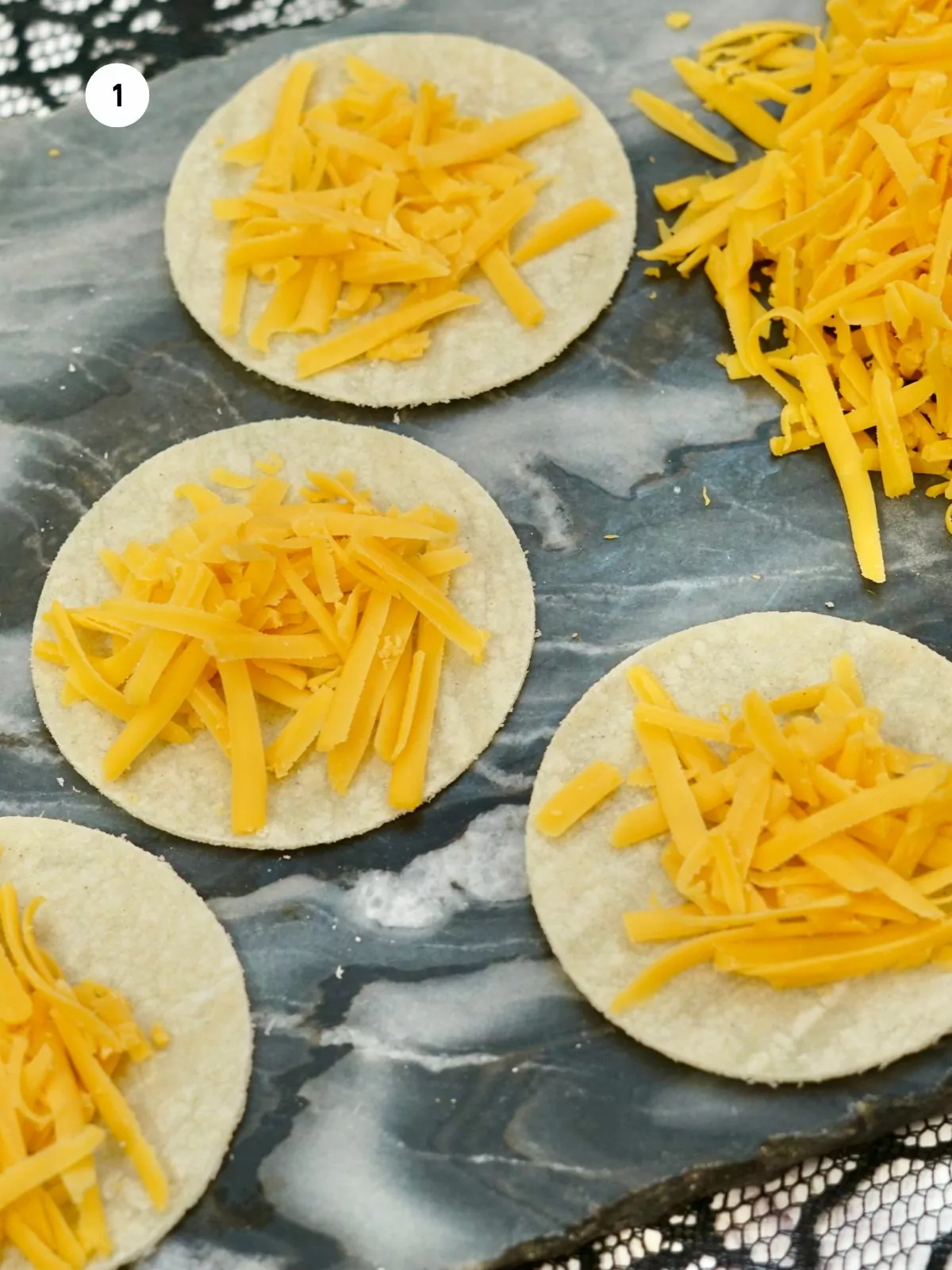 shredded cheddar cheese on top of flour tortillas.