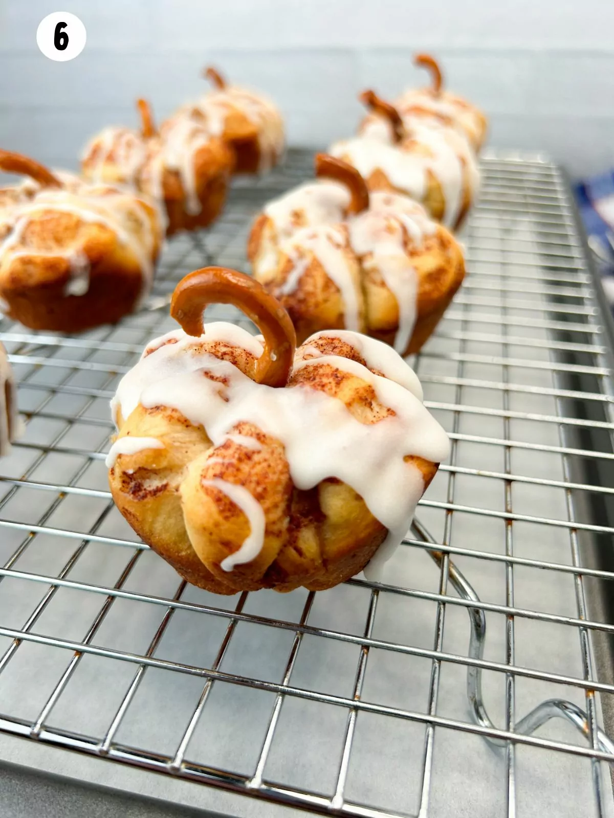 baked rolls with glaze and pretzel twists to form stems on cooling rack.