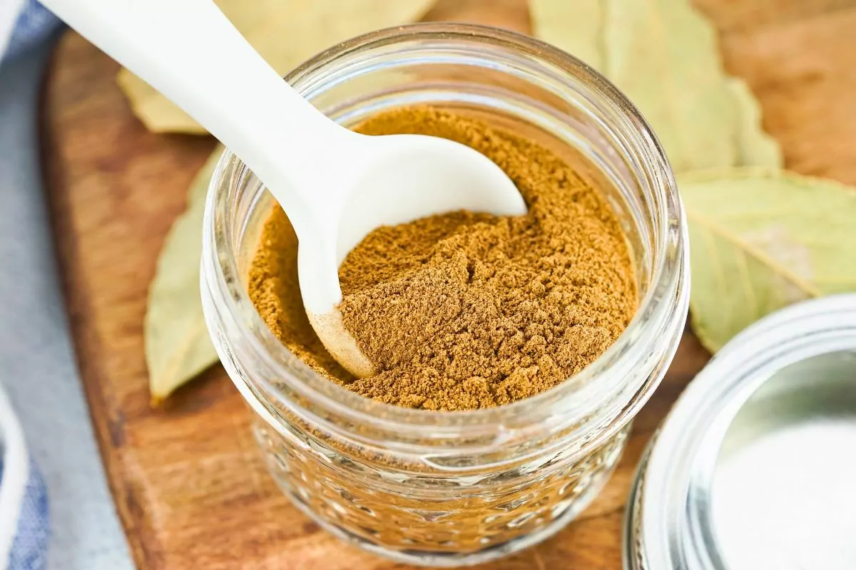 homemade allspice in small mason jar with white spoon.