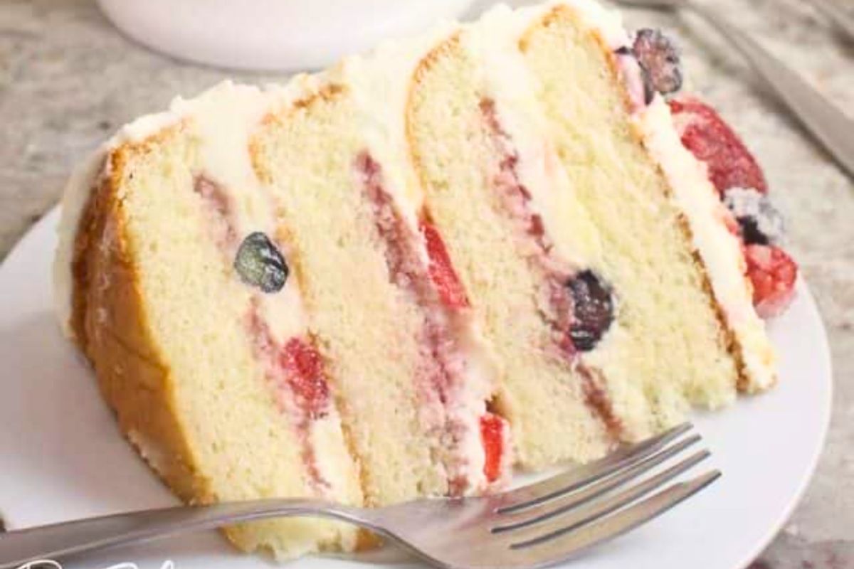 a slice of cake in a plate with strawberry raspberry and blueberry