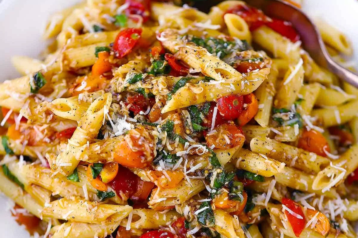 a plate of pasta with cheese tomato and parsley