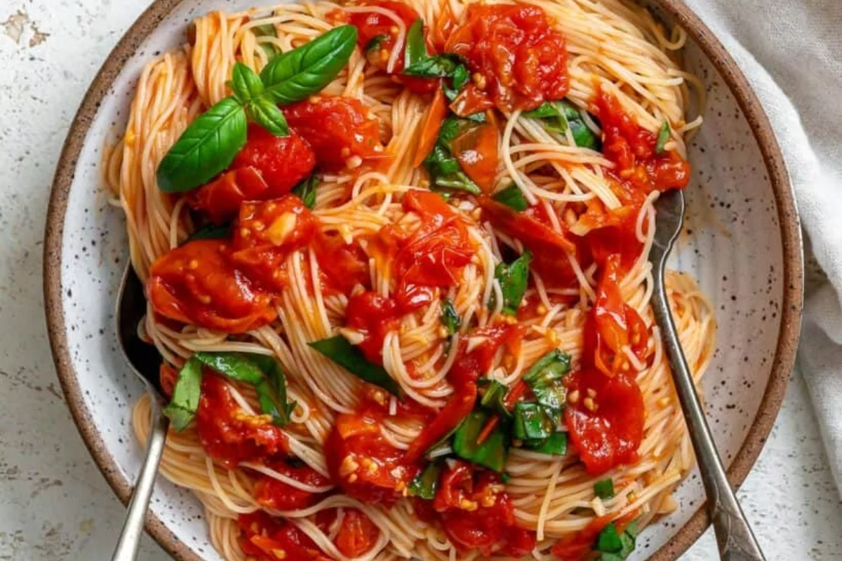 a plate of hair spaghetti pasta with spinach and tomatoes