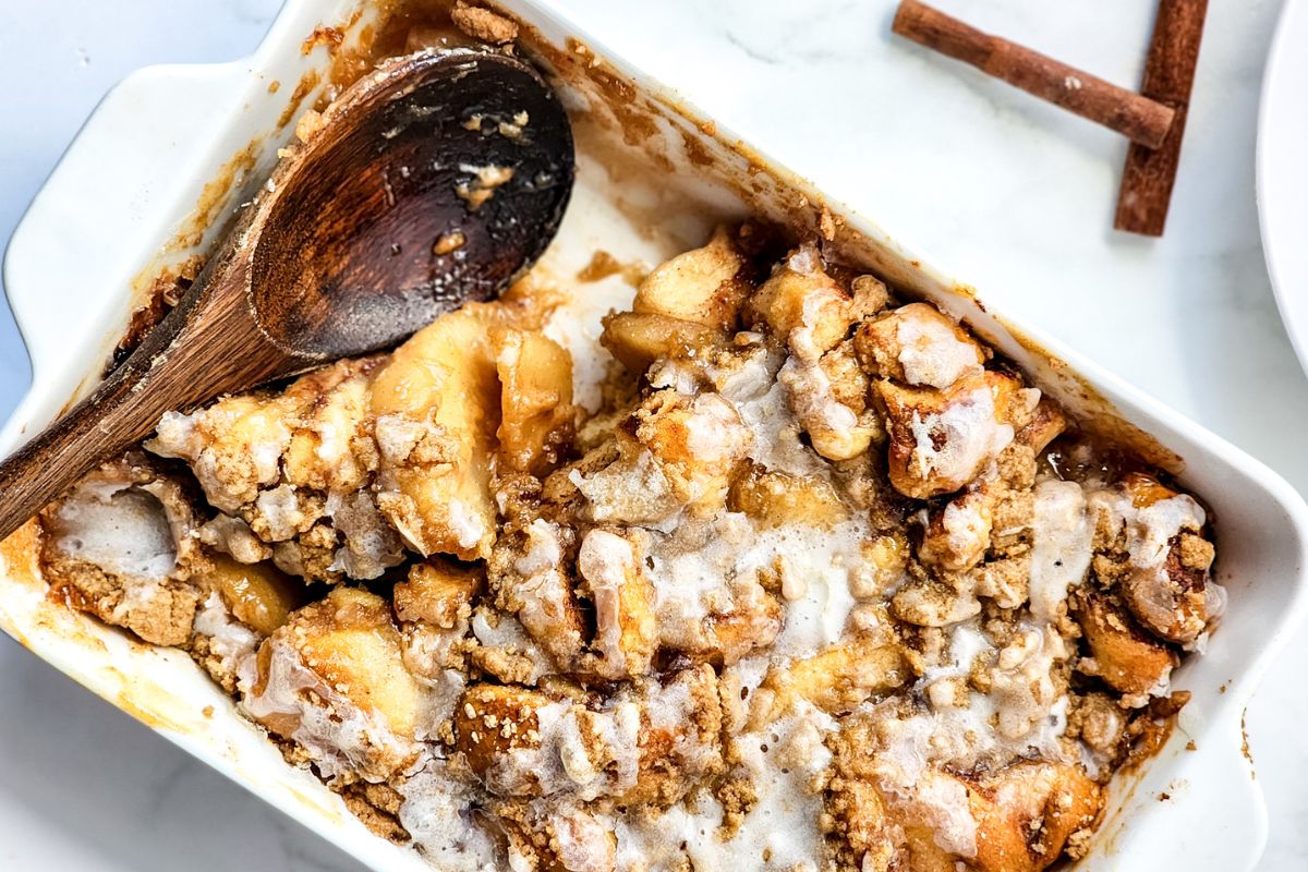 Apple Cinnamon Roll Casserole with a wooden spoon where a scoop has been taken out.