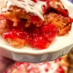 close up of a plate of cherry pie cinnamon rolls with the slow cooker in the background