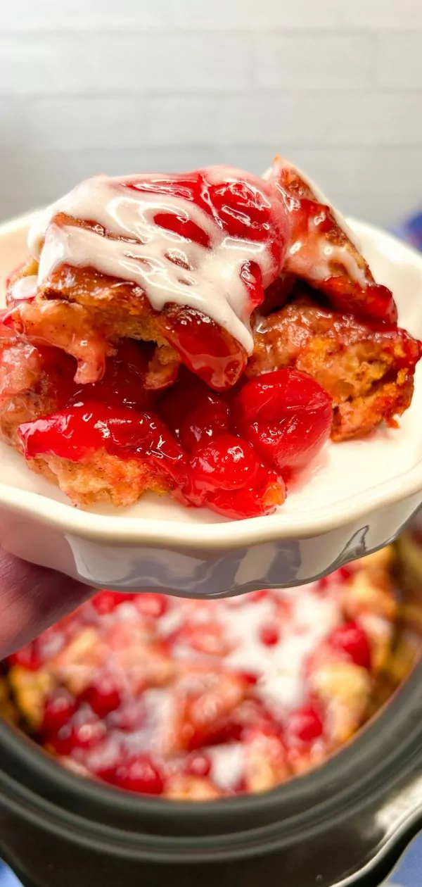 close up of a plate of cherry pie cinnamon rolls with the slow cooker in the background