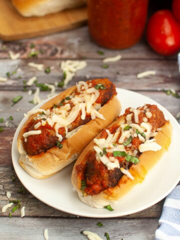 2 meatball sandwiches served on a white plate.