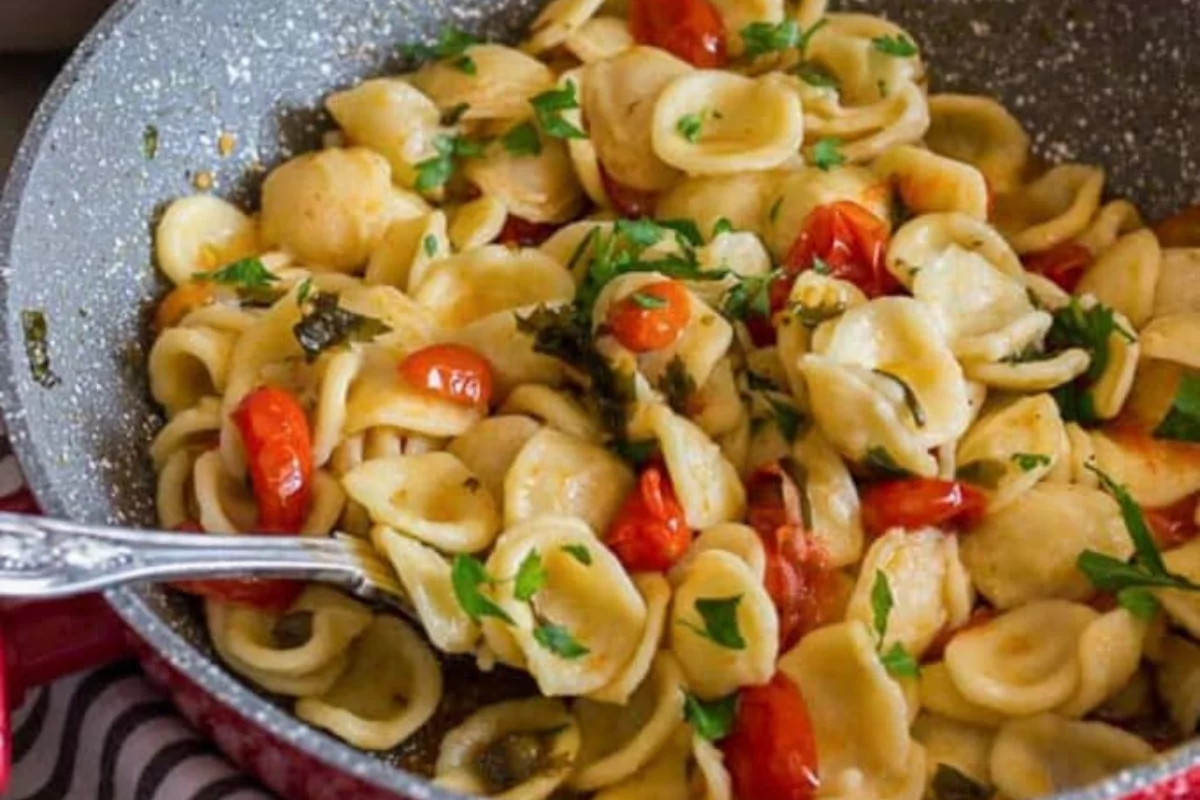 a bowl of pasta with parsley and tomato