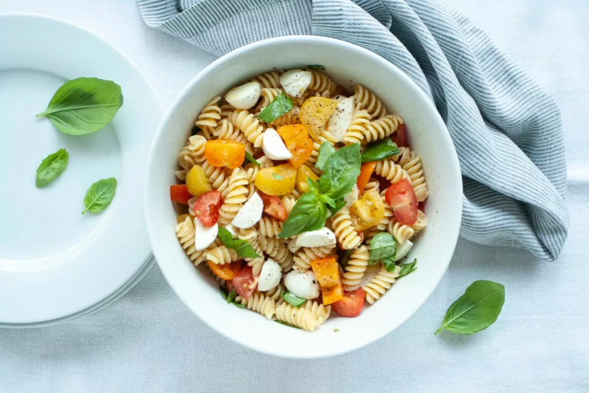 bowl of pasta with fresh tomatoes, cheese and fresh basil.