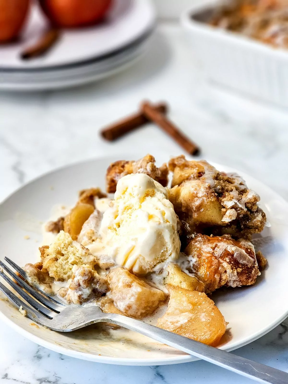 apple cinnamon roll casserole served with a scoop of vanilla ice cream