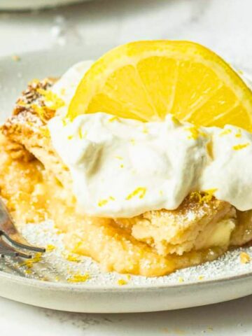 a lemon cake in a plate top with cool whip and lemon