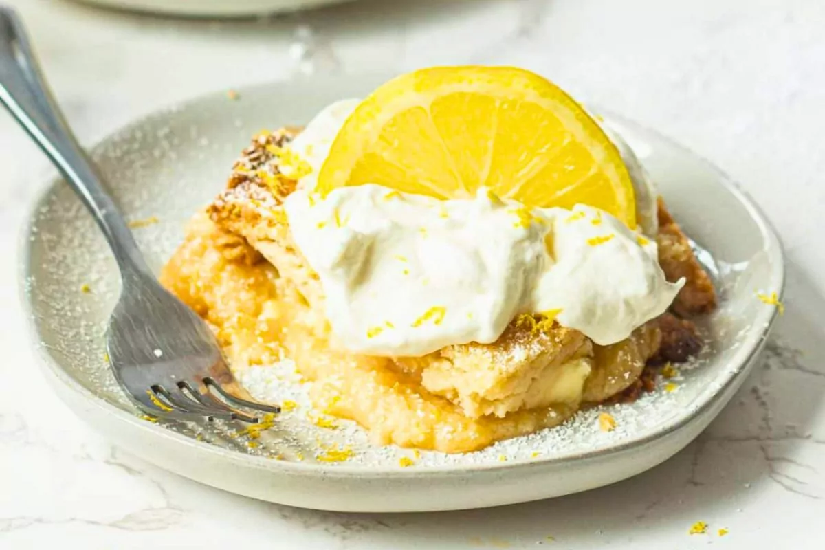 a lemon cake in a plate top with cool whip and lemon